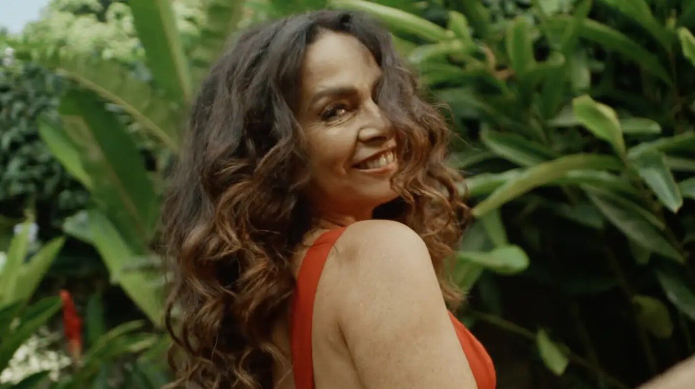 Cláudia Ohana sorrindo entre folhagens